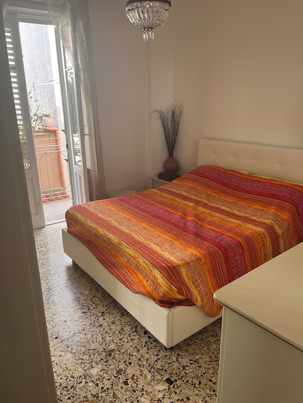 A bedroom with a bed, a nightstand, a vase, and a chandelier. - Casa di Filippo (Sicilia)