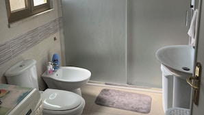 Ein Badezimmer mit Toilette, Bidet, Waschmaschine und Duschkabine.