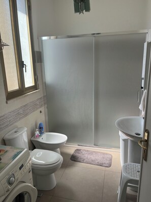 A bathroom with a toilet, bidet, washing machine, and a shower enclosure. - Casa di Filippo (Sicilia)