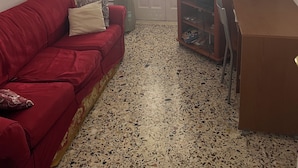 Ein Wohnzimmer mit einem roten Sofa, einem Holzschrank und einem Fernseher auf einem Schrank.