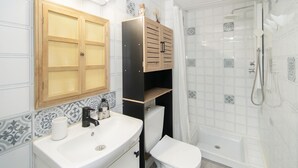 Baño con lavamanos, inodoro, ducha y armarios de madera.
