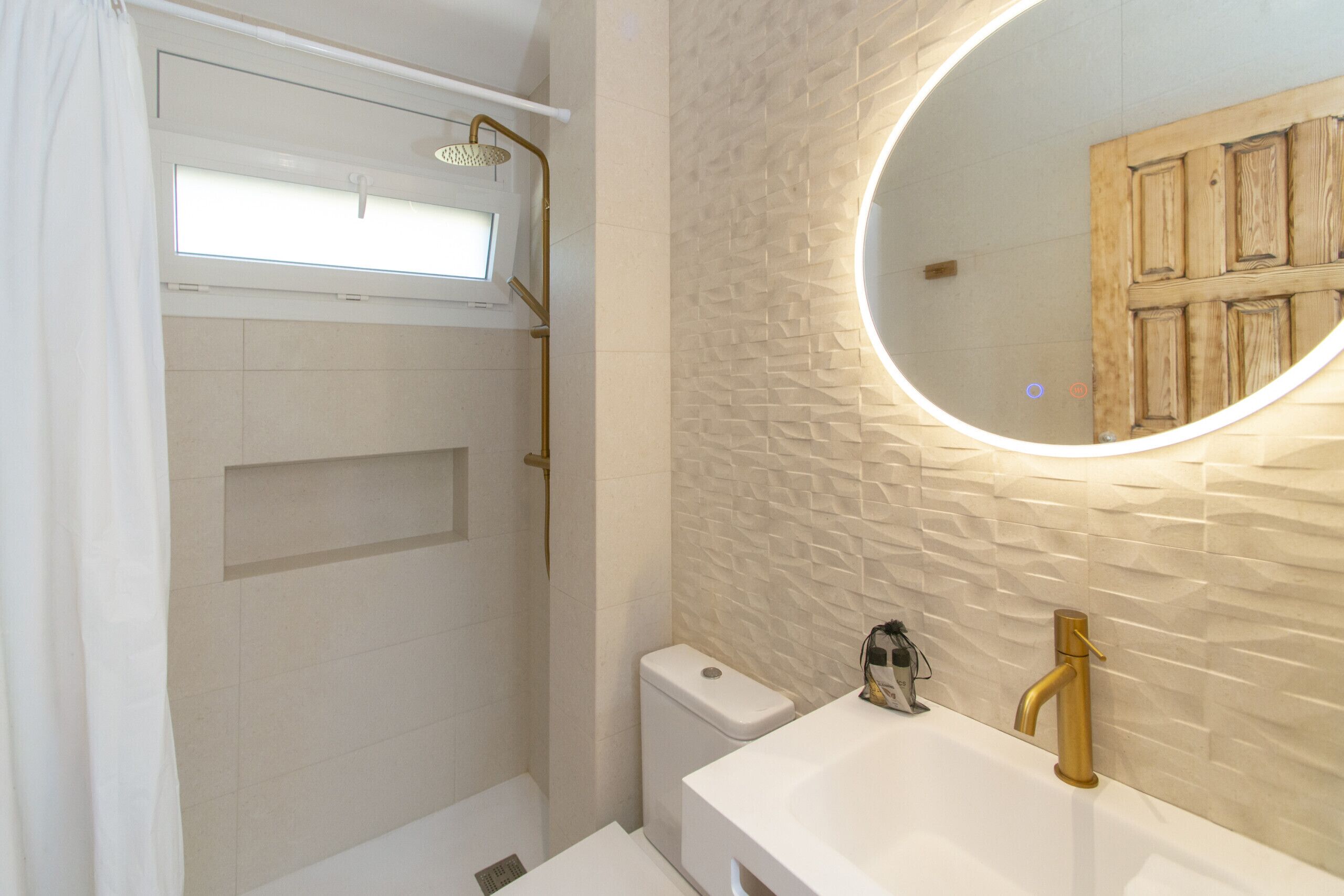 A bathroom with a shower, toilet, sink, and a mirror.