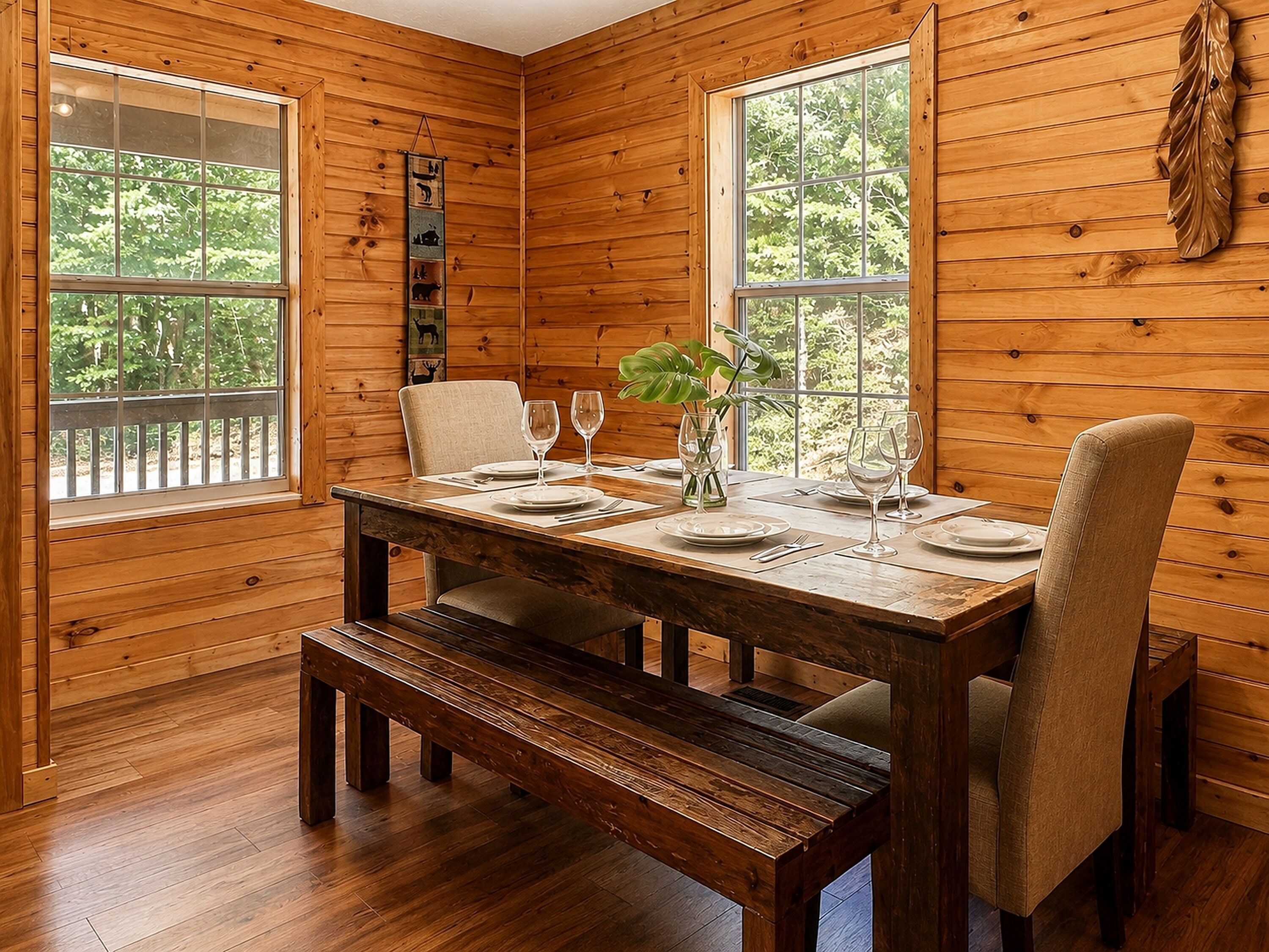 A wooden interior with a dining table set for two, two chairs, and a bench.