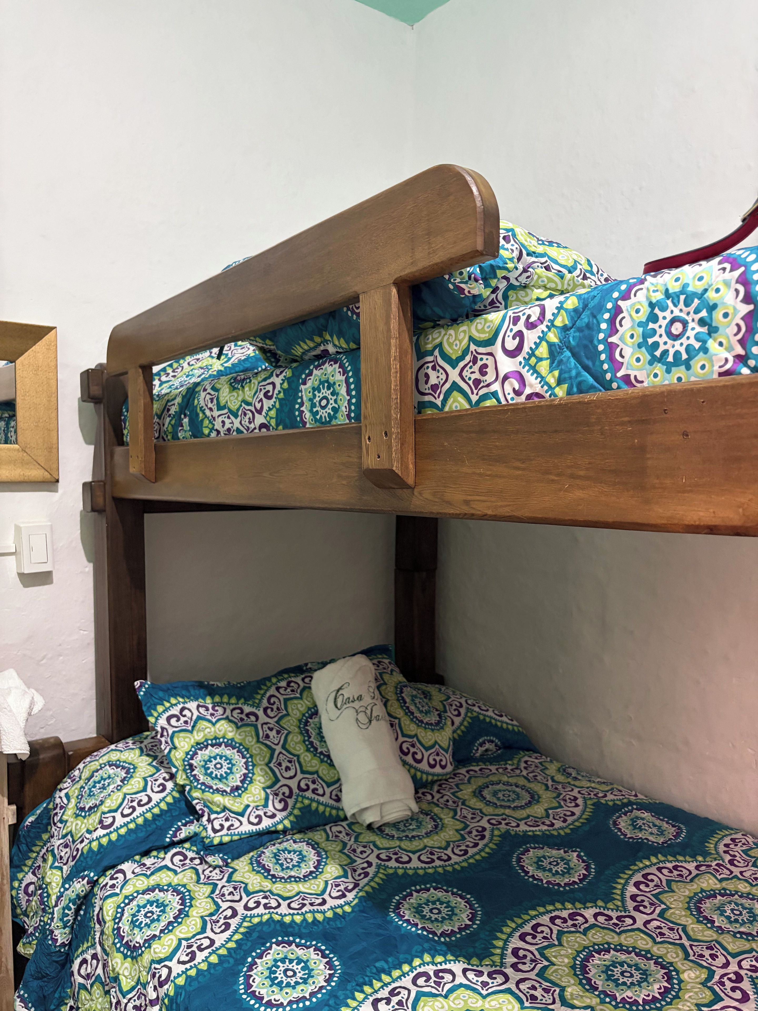 Una cama litera con una colcha estampada y una toalla blanca en la cama inferior.
