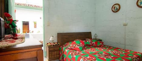 A bedroom with a bed, a nightstand, a dresser, and a window with a view of the outside.