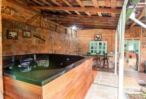 Un baño rústico con una bañera de madera, paredes de piedra y un armario verde.