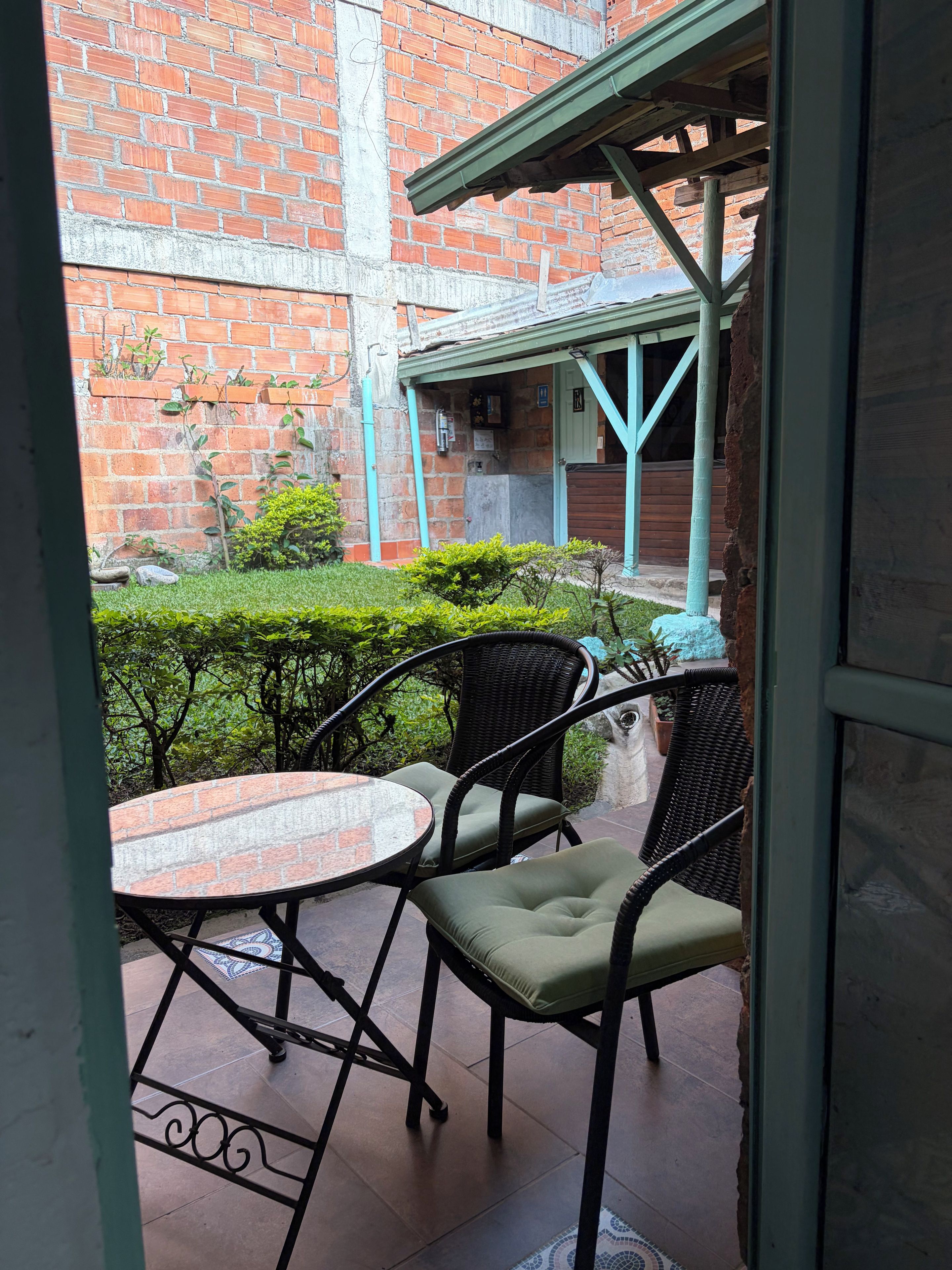 An outdoor patio area with a brick wall, a covered seating area, and a small garden.