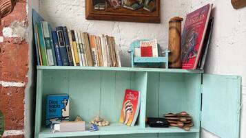 A room with a bookshelf filled with books, a painting, and a small table with a toy car and a blue decorative item.