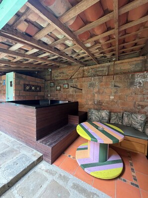 A rustic interior with a wooden bench, a colorful table, and a brick wall. - Casa Duque Jardin (Jardín)