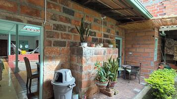 A covered patio area with brick walls, tiled flooring, and potted plants.