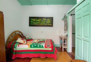 Un dormitorio con cama, mesita de noche, un cuadro en la pared y una puerta.