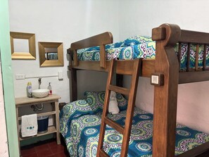 Un lit superposé avec une échelle, une table de chevet avec un lavabo et un miroir.