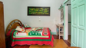 Un dormitorio con cama, mesita de noche, un cuadro en la pared y una puerta.