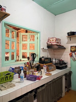 Una cocina con ventana, estufa y varios utensilios sobre la encimera.