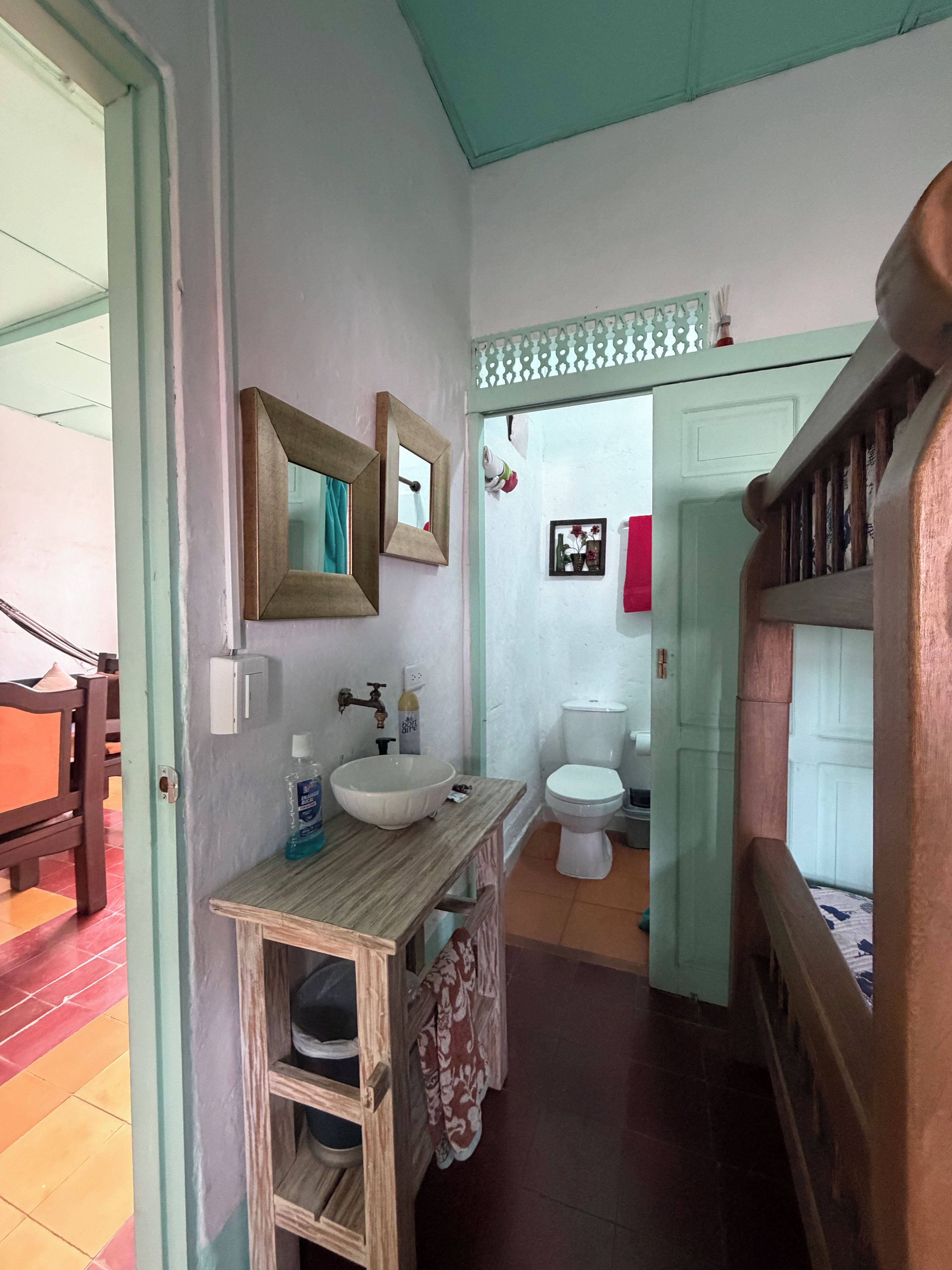 A bathroom with a wooden vanity, a sink, a toilet, and a mirror.
