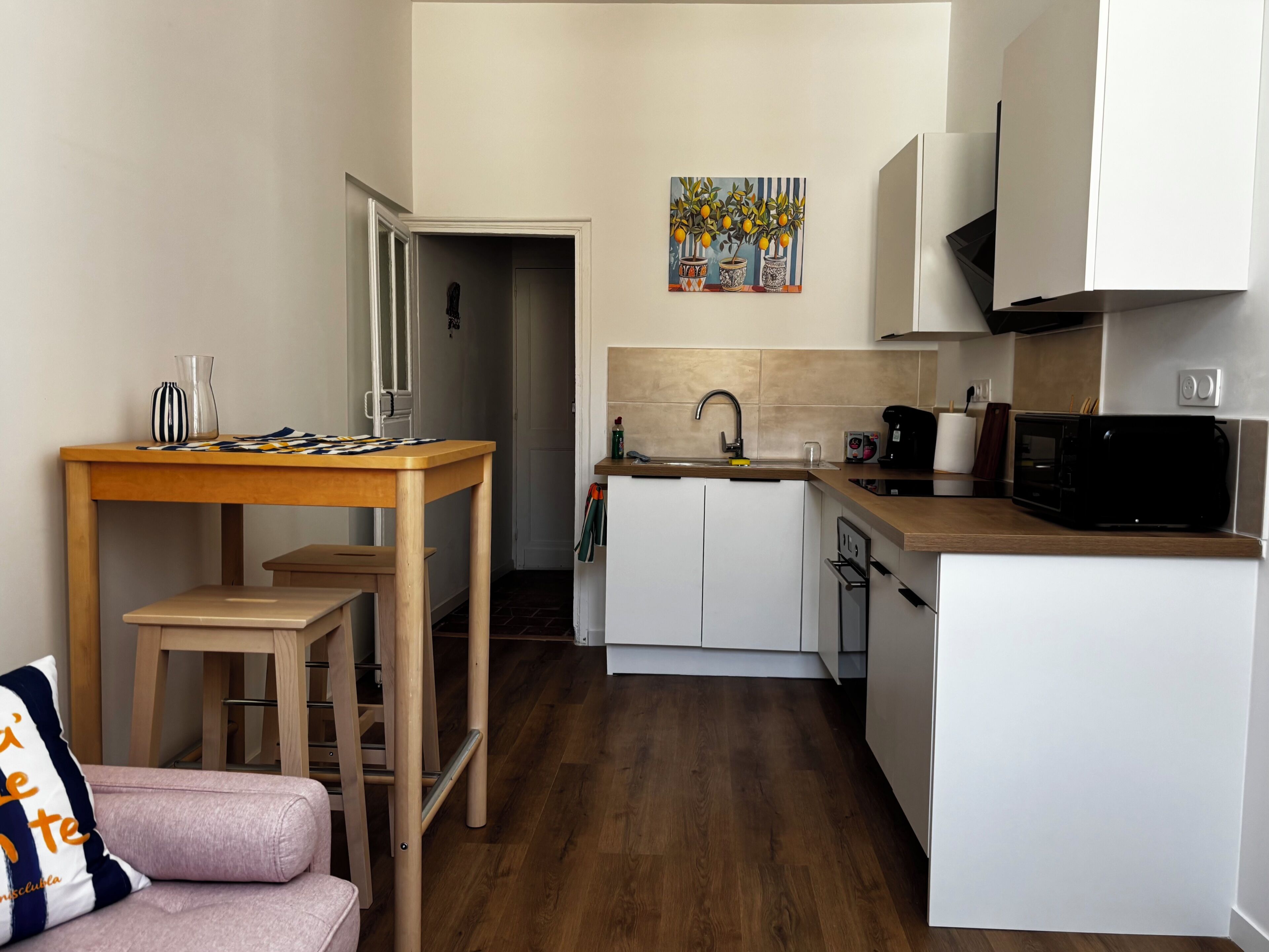 Une cuisine de taille réduite, avec une table en bois, un four à micro-ondes et un évier.