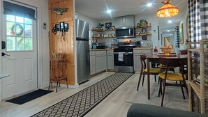 Eine moderne Küche mit Kühlschrank, Mikrowelle und Herd. Ein Essbereich mit Tisch und Stühlen vorhanden.