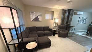 A living room with a sectional sofa, a round coffee table, a floor lamp, and a fireplace. - 1-bedroom apartment with AC near Lake Oroville (Oroville)