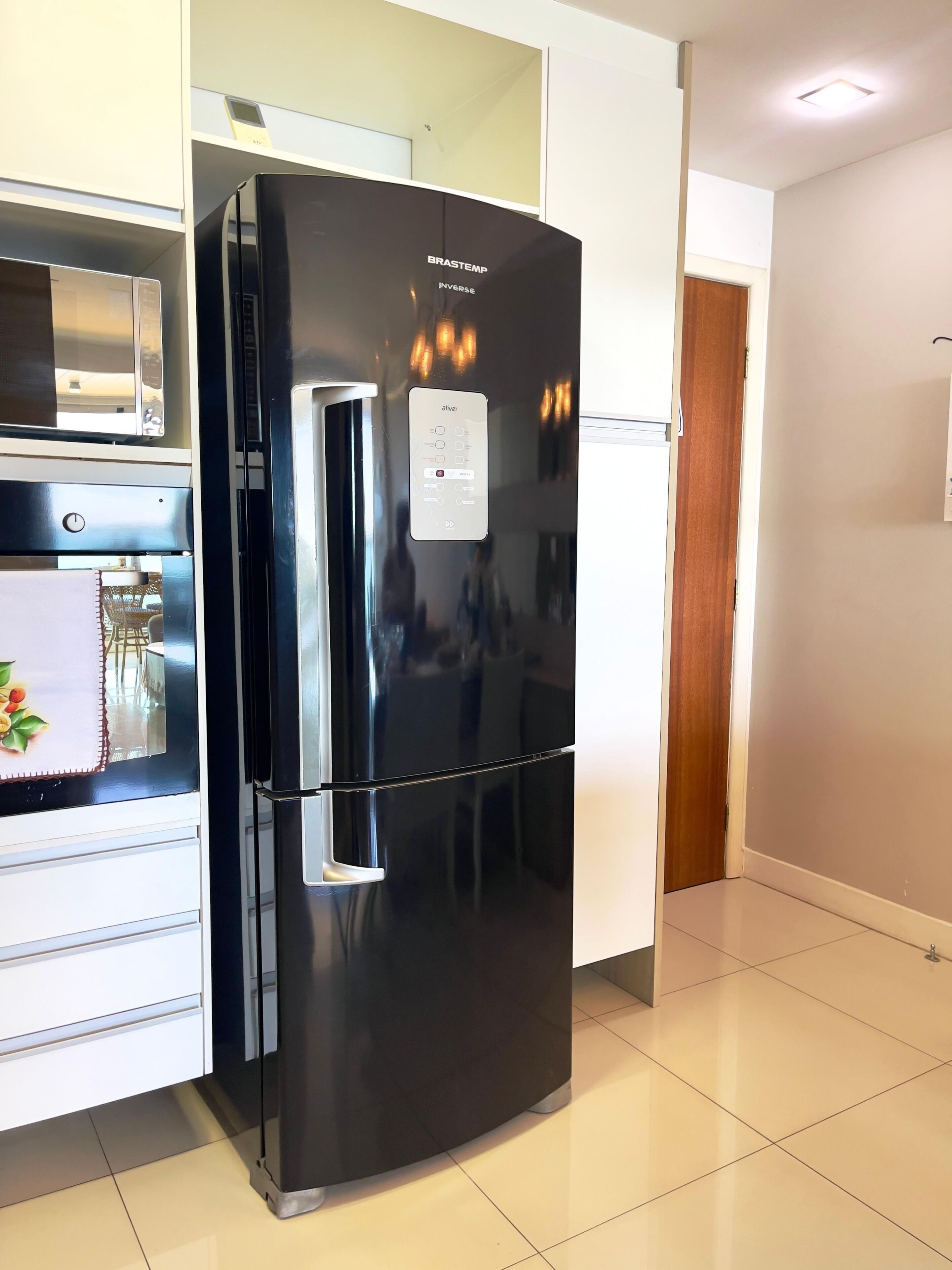Una cocina moderna con un refrigerador negro, un microondas y un armario blanco.