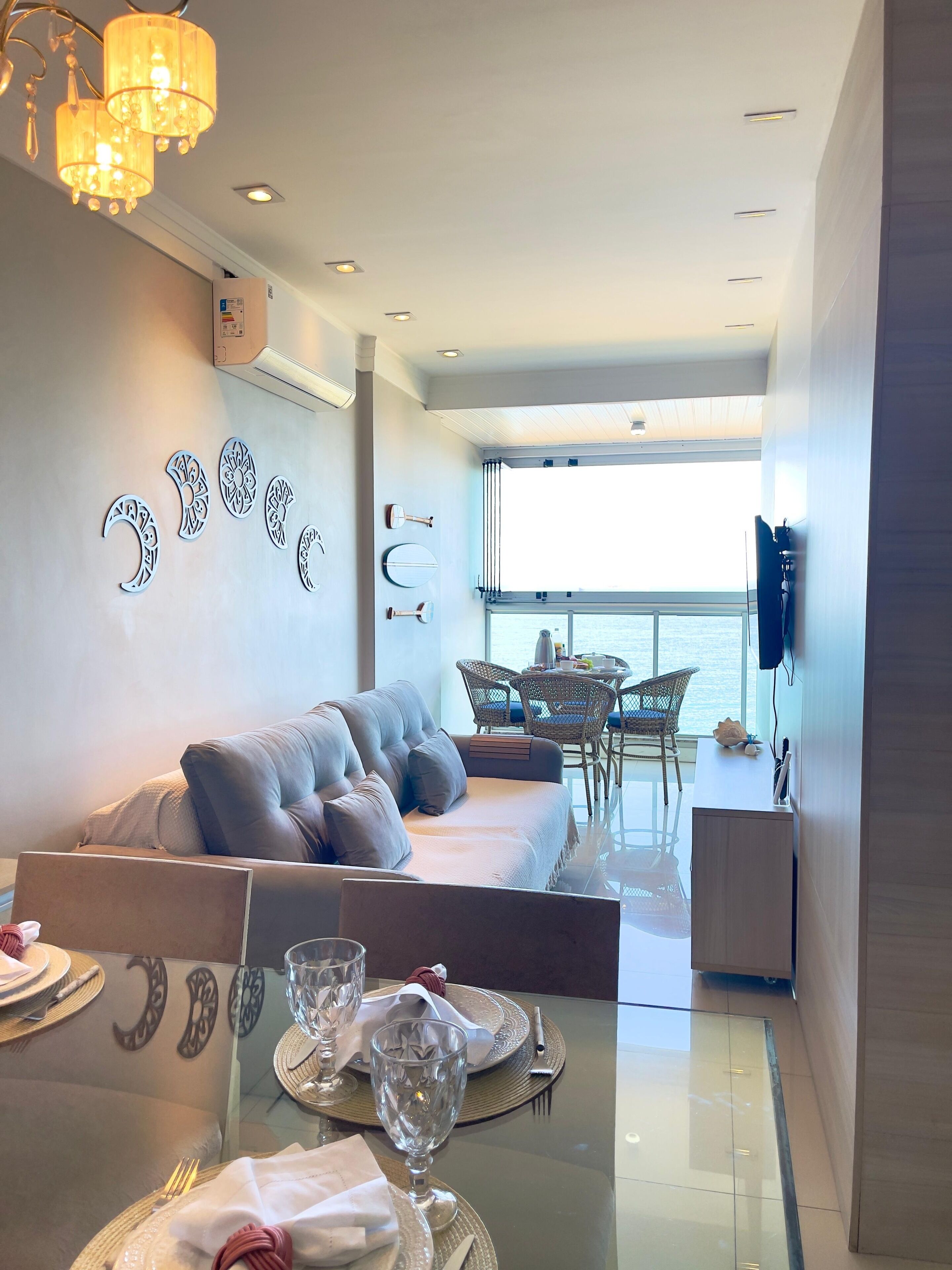 Ein modernes Wohnzimmer mit einer Couch, einem Esstisch für zwei Personen und einem Balkon mit Blick.