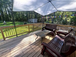 A covered deck with wooden flooring, a bench, and a table. - Zen Retreat • Huge Yard • 3 Min to Downtown Cary (Cary)