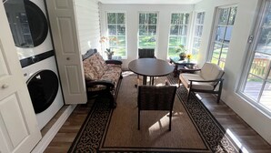 Una habitación iluminada por el sol, con un ventilador de techo, un sofá, una mesa y sillas.