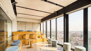 Un intérieur moderne avec un coin salon, de grandes fenêtres et une vue sur la ville.