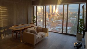 Un salon moderne avec une grande fenêtre, une table à manger, un canapé et une plante en pot.