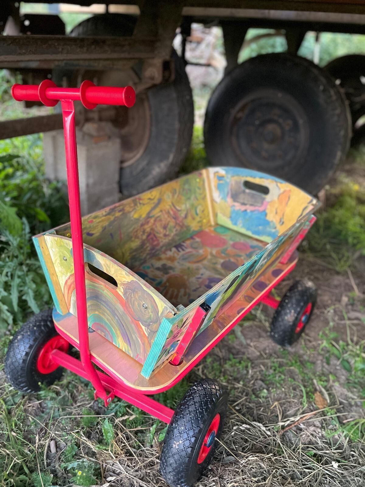 Ein roter Wagenrad mit einem bunten, abgenutzten Behälter.