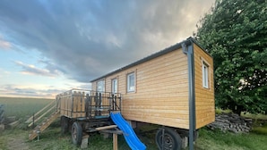 A small wooden house with a blue slide and a wooden deck.