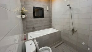 Ett modernt badrum med badkar, toalett och dusch.