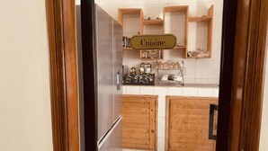 Ett kök med träskåp, ett kylskåp i rostfritt stål och en skylt med texten ”Kök”.