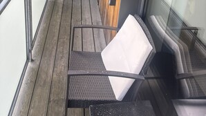 A balcony with a metal railing, a wooden wall, and a window.