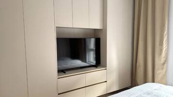 Een slaapkamer met een bed, een aan de muur bevestigde televisie en een kledingkast.