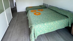 Een kamer met twee bedden, een kledingkast en een deur die naar een andere kamer leidt.