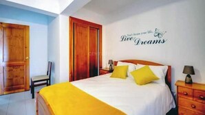 A hotel room with a bed, two bedside tables, a chair, and a wall with a motivational quote. - Nazaré - 10 minutes from the ocean (montholon)