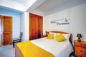 A hotel room with a bed, two bedside tables, a chair, and a wall with a motivational quote. - Nazaré - 10 minutes from the ocean (montholon)