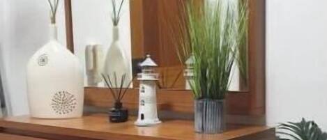 A wooden desk with a mirror, a vase, and a potted plant.