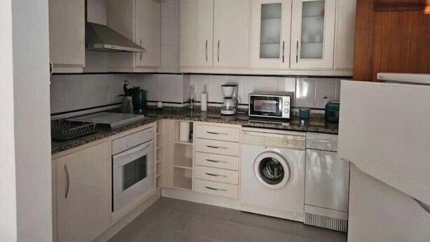 A compact kitchen with a microwave, oven, and washing machine. - Nazaré - 10 minutes from the ocean (montholon)