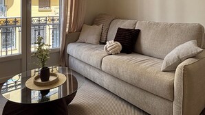 Uma sala de estar com sofá, mesa de centro e janela com cortinas.