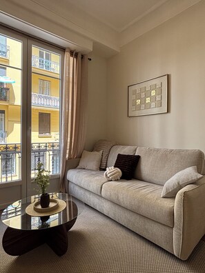 Ein Wohnzimmer mit einer Couch, einem Couchtisch und einem Fenster mit Vorhängen.
