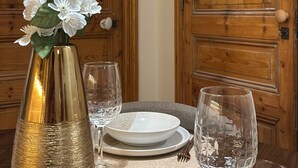 Uma mesa de jantar com um vaso de flores brancas, um prato e um copo.