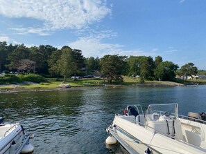A lake with a boat docked on the right, surrounded by trees and a few houses in the background. - 5 Star Holiday Home in Uddevalla (Uddevalla)