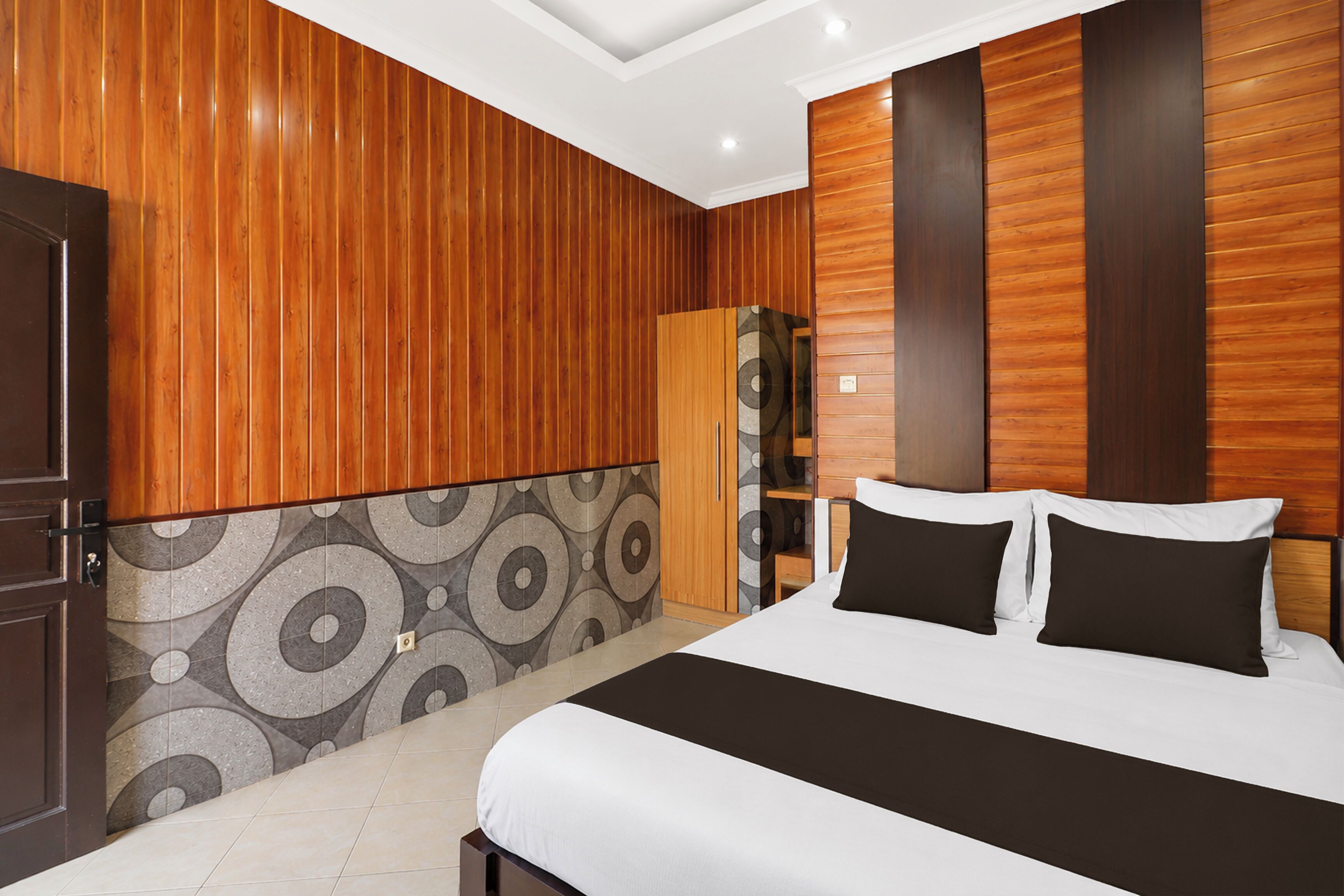 Une chambre avec un lit, des murs recouverts de panneaux en bois, une armoire et un mur recouvert de carreaux décoratifs.