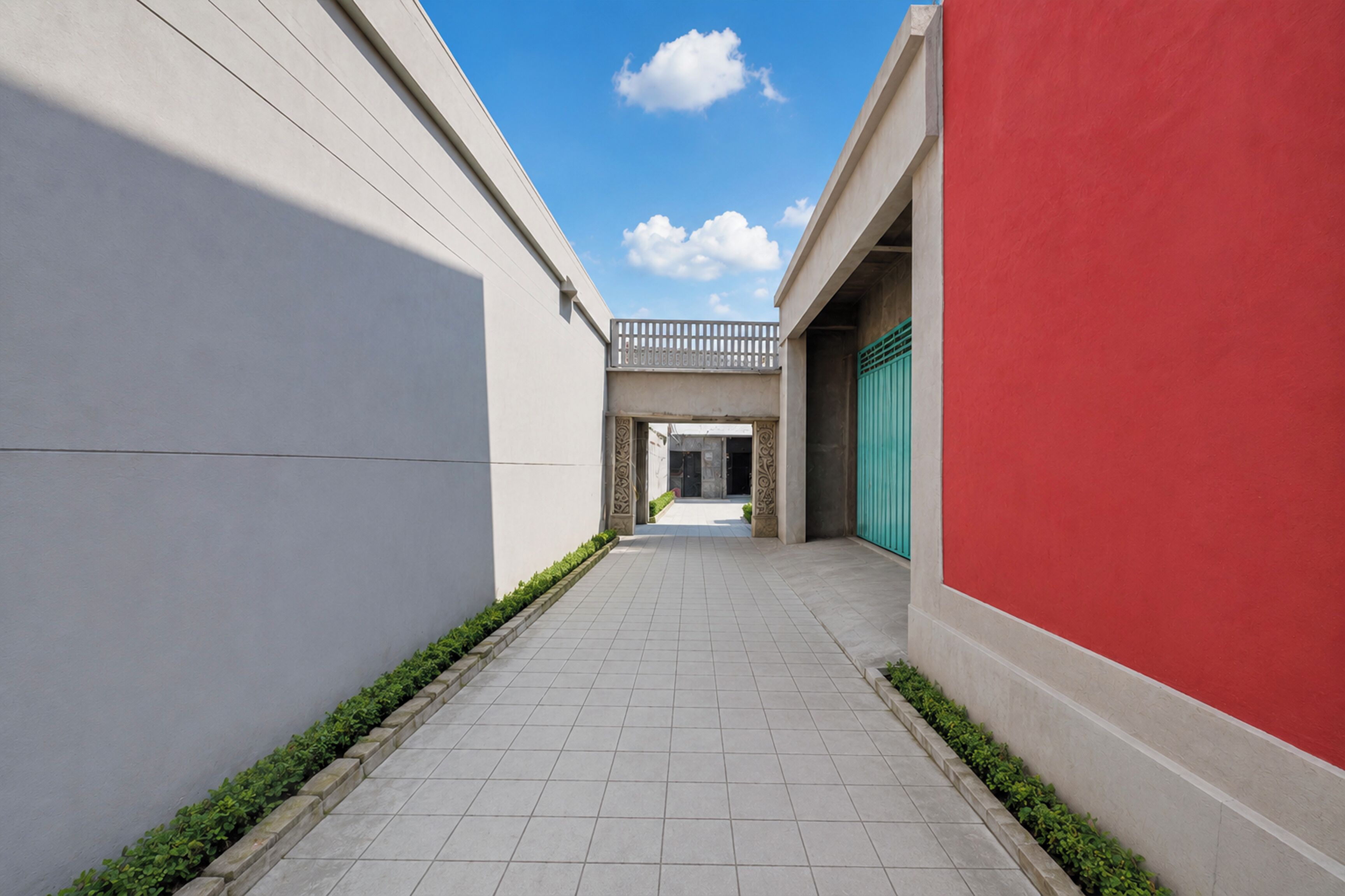 A narrow corridor with tiled flooring, a red wall on the right, and a white wall on the left.