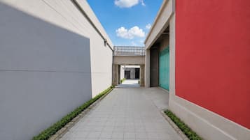 A narrow corridor with tiled flooring, a red wall on the right, and a white wall on the left.