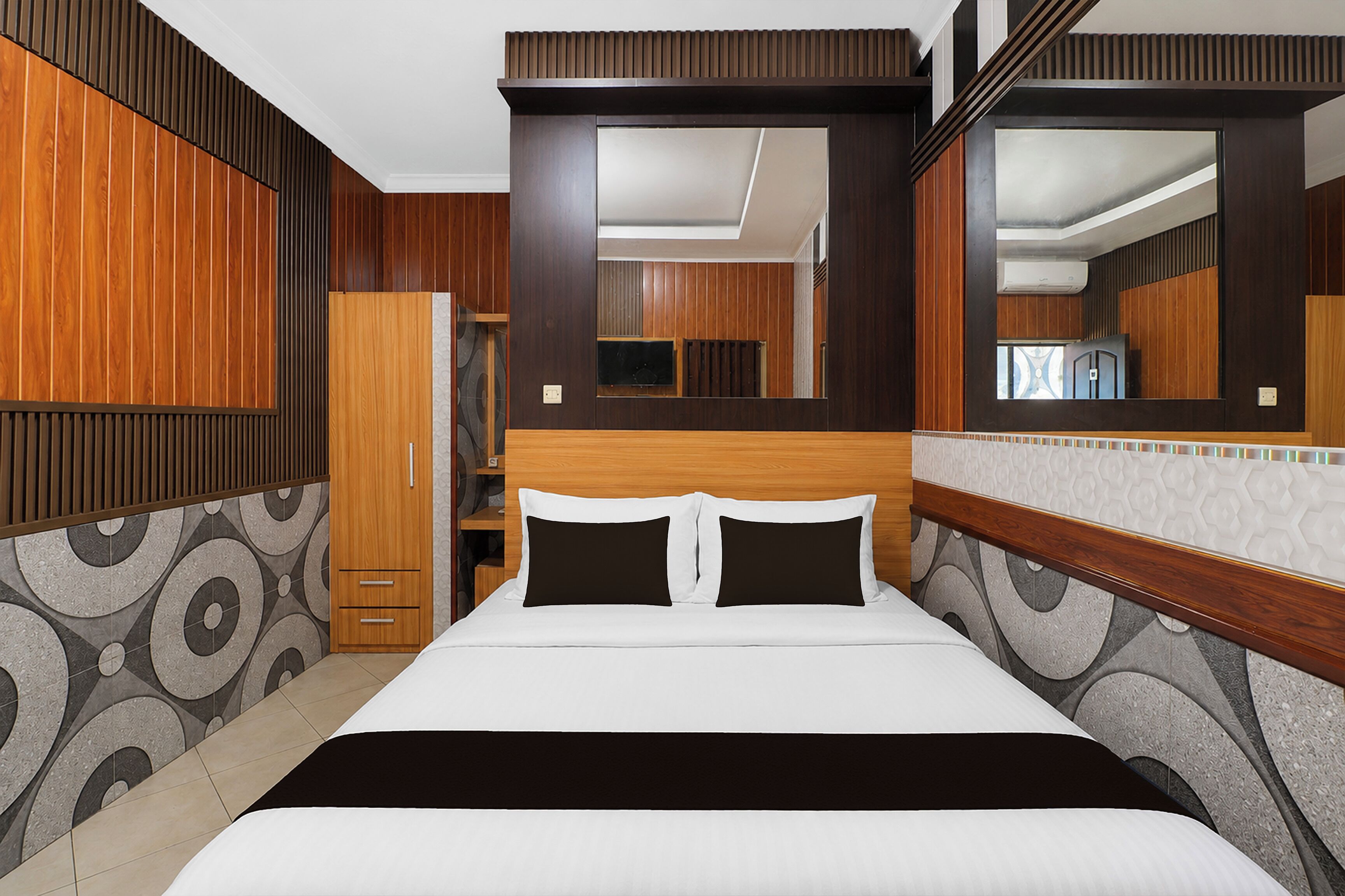Una habitación de hotel con una cama grande, paneles de madera, un espejo y un armario.