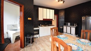 Una cocina compacta con estufa, horno, microondas y refrigerador. Cuenta con una mesa de comedor con sillas y un lavamanos pequeño.