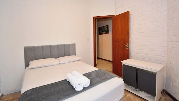 Un dormitorio con una cama, una mesita de noche y una puerta que da a otra habitación.