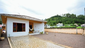 Una casa con patio de tejas, una hamaca y vistas a una colina.